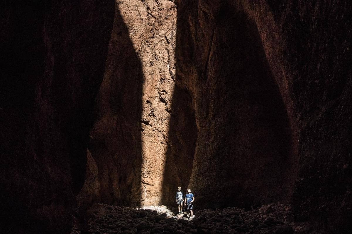 Couple standing in the dark Echidna Chasm in a ray of light.