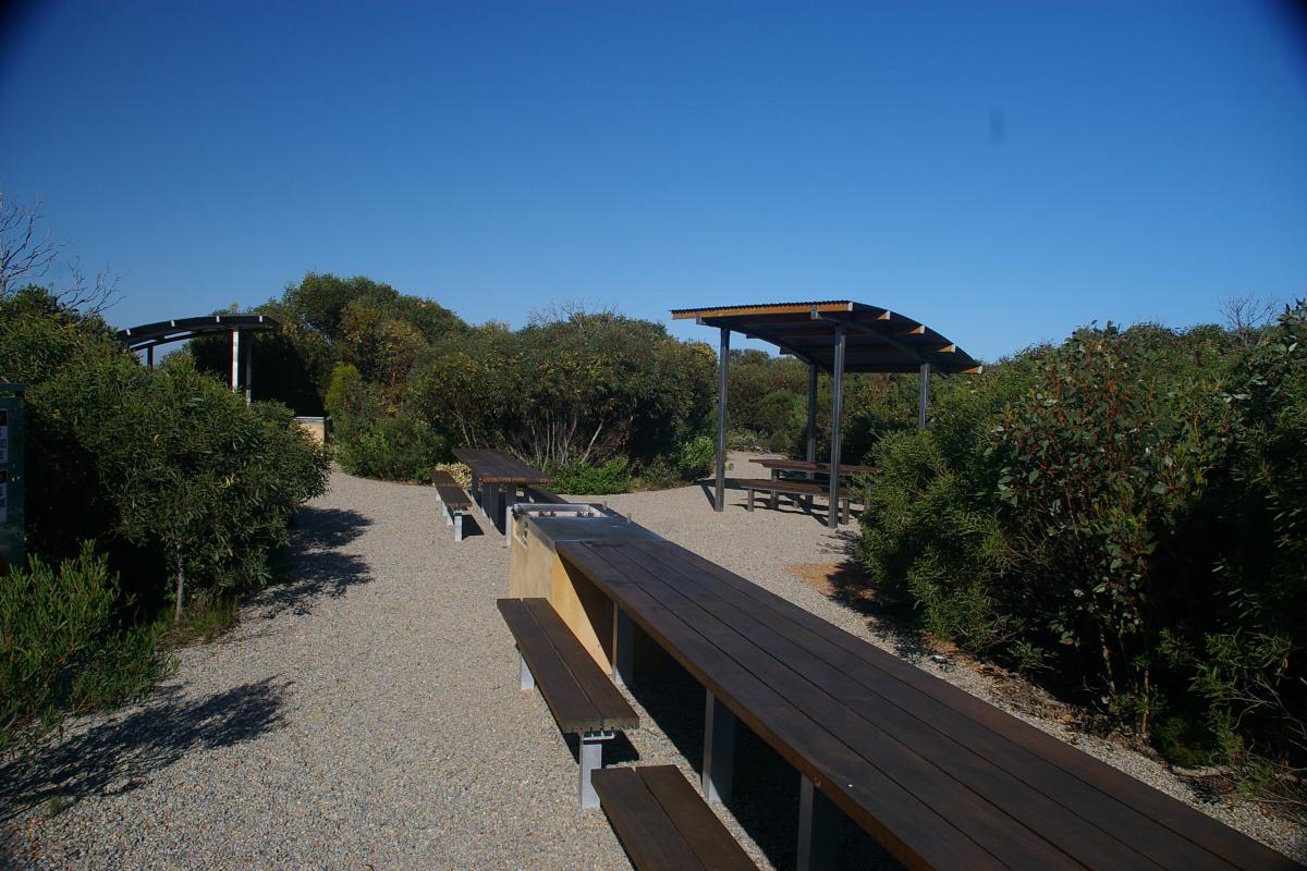 wooden visitor picnic benches at Four Mile Beach Campground