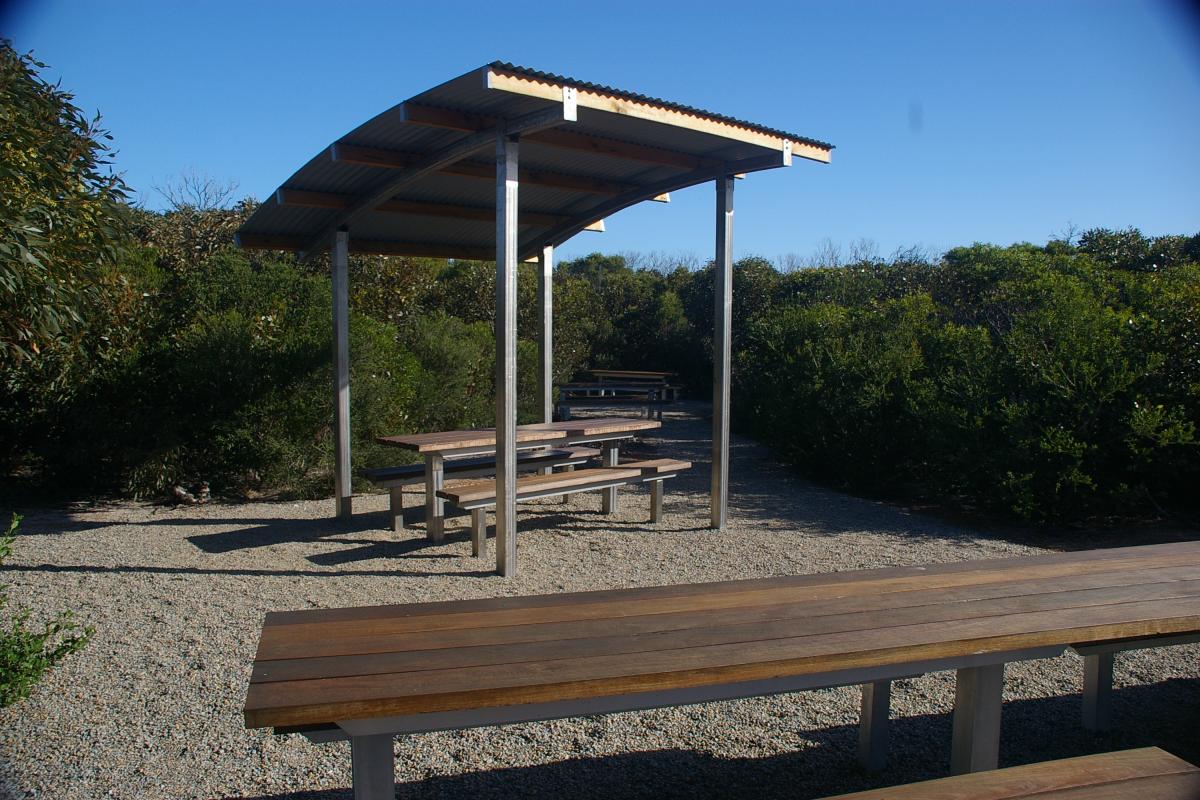 wooden visitor picnic benches at Four Mile Beach Campground