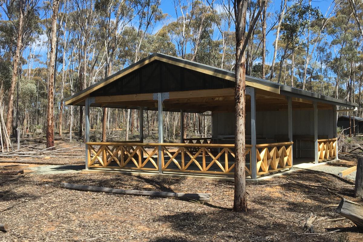 shelter over picnic tables with woodlands in the background