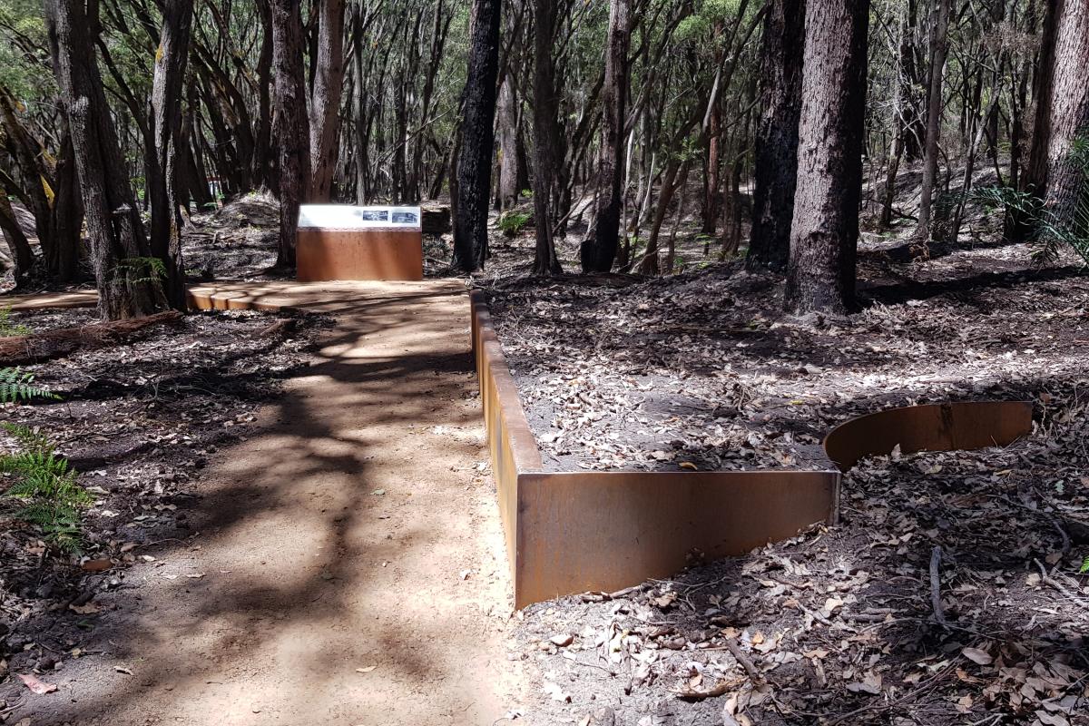 Walk trail through bushland and interpretive sign at the end of the path