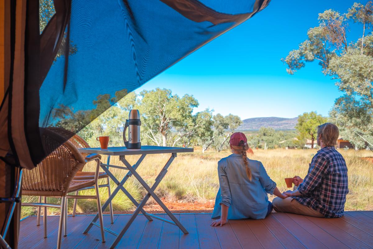 Two people sitting on eco tent verandah enjoying the view