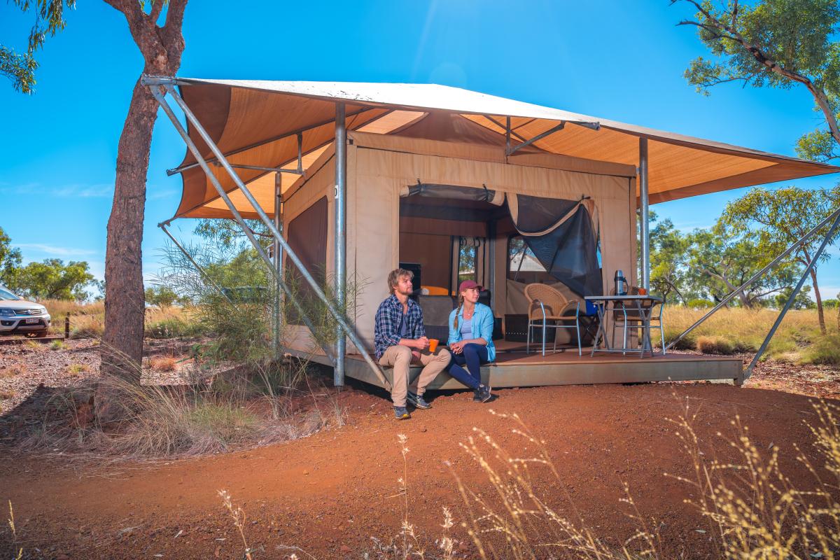 Two people sitting on verandah of glamping tent