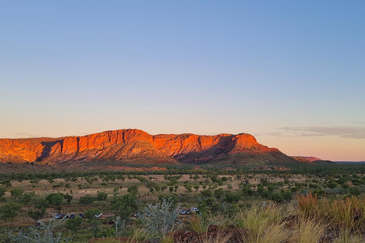 Sunset views from Kungkalanayi Lookout to the Bungle Bungle Ranges creating soft shades of colour of the grass and trees in the foreground.