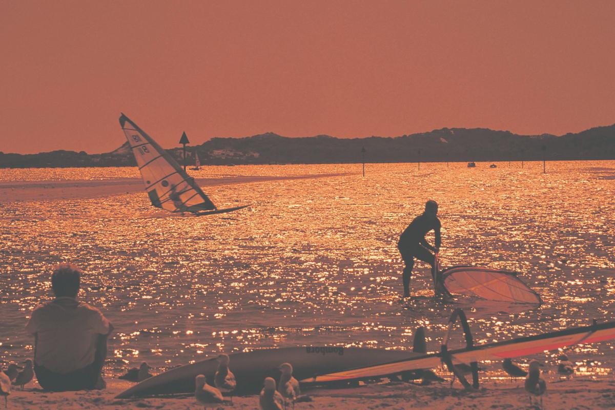 people windsurfing on a lake with an orange filter on the image 
