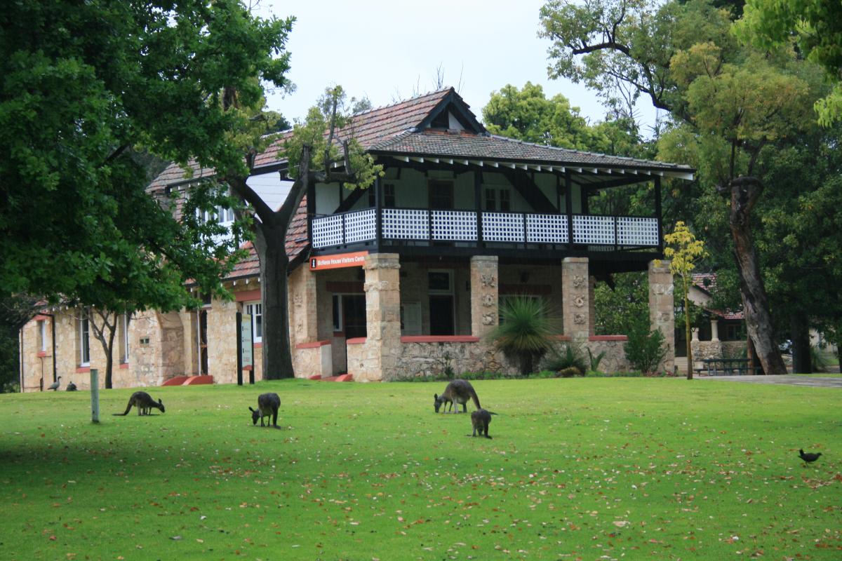 Historical old stone building nestled among trees and plenty of green grass.