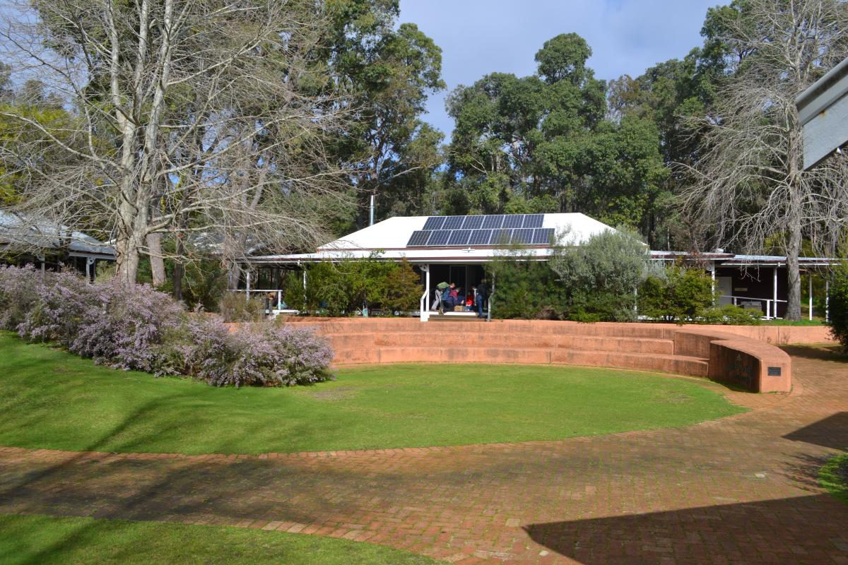 Buildings and grassed area with seating for school gatherings surrounded by bushland