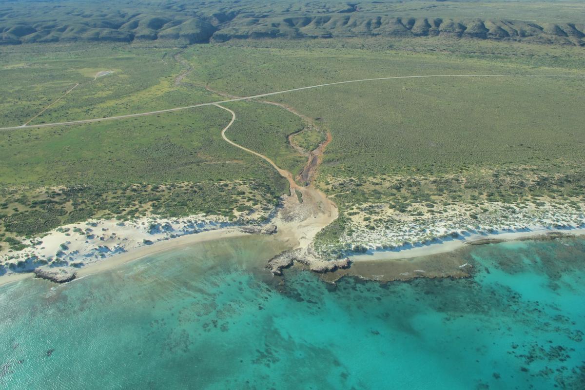 Aerial view of clear blue water and dirt roads leading through scrub