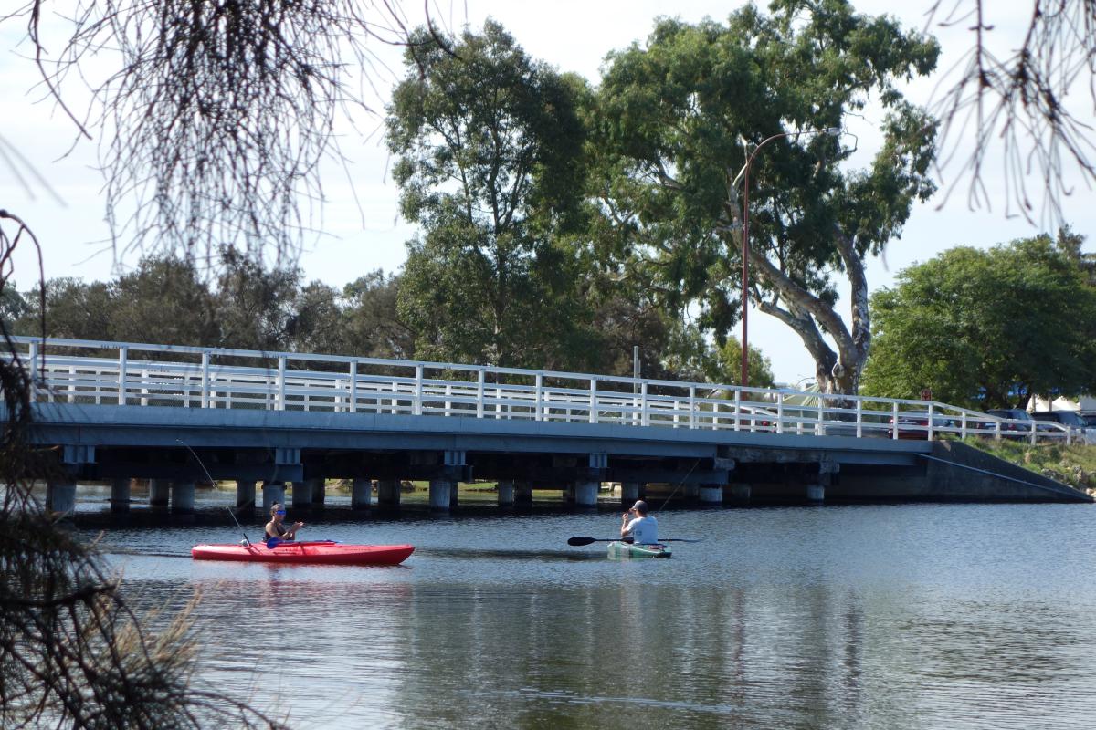 Bridge across the river with kayakers paddling underneath.