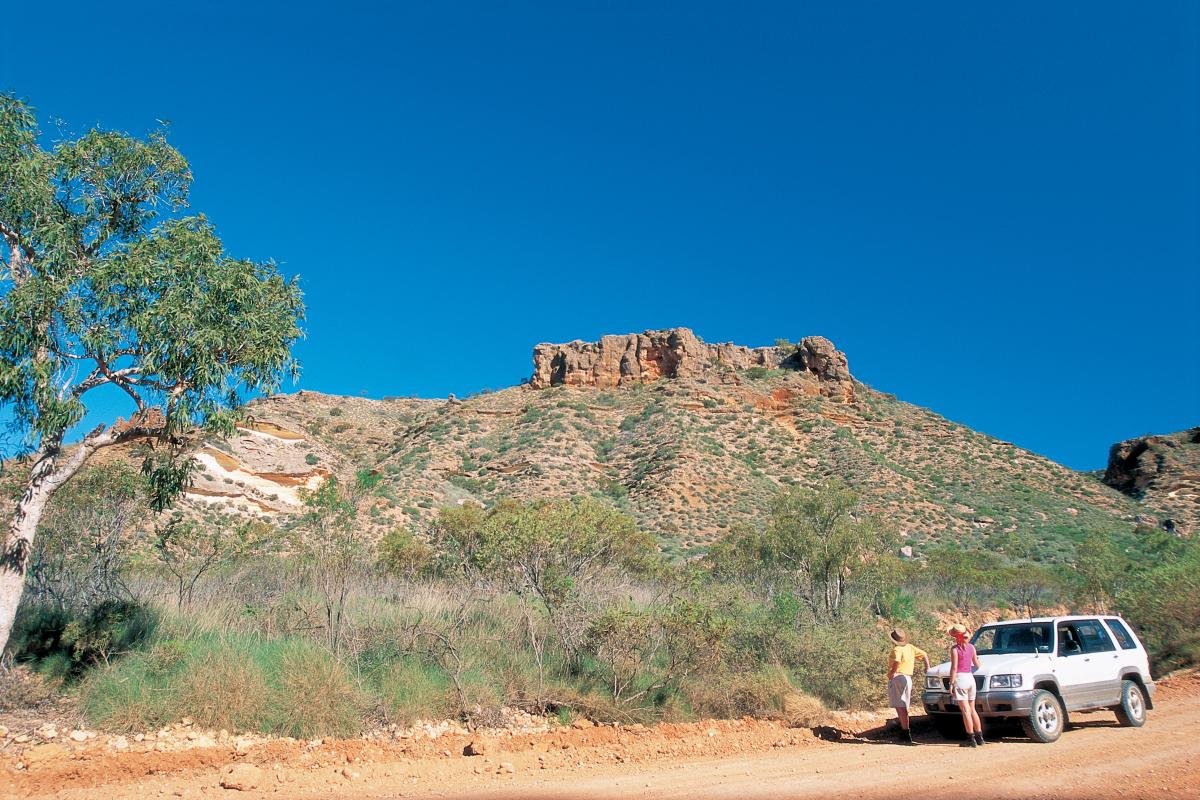 Two people standing near a four-wheel drive ina canyon.