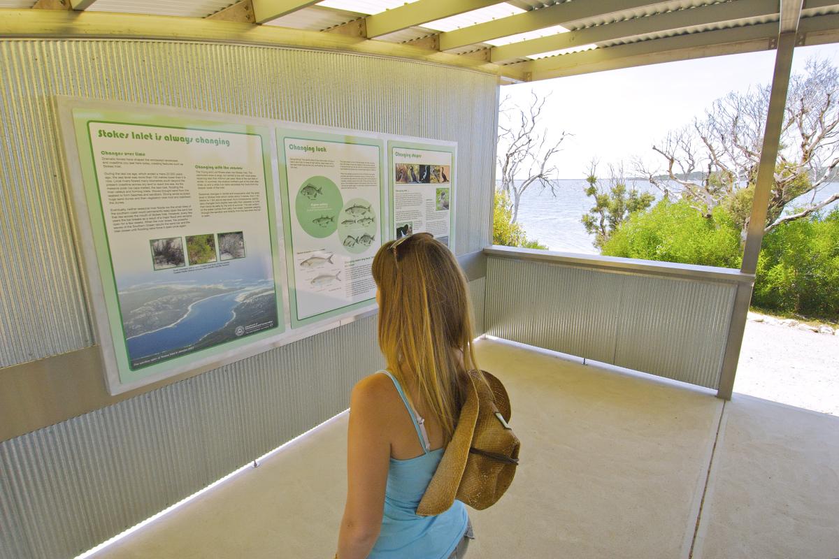 Visitor reading the interpretive signage with inlet views in the background