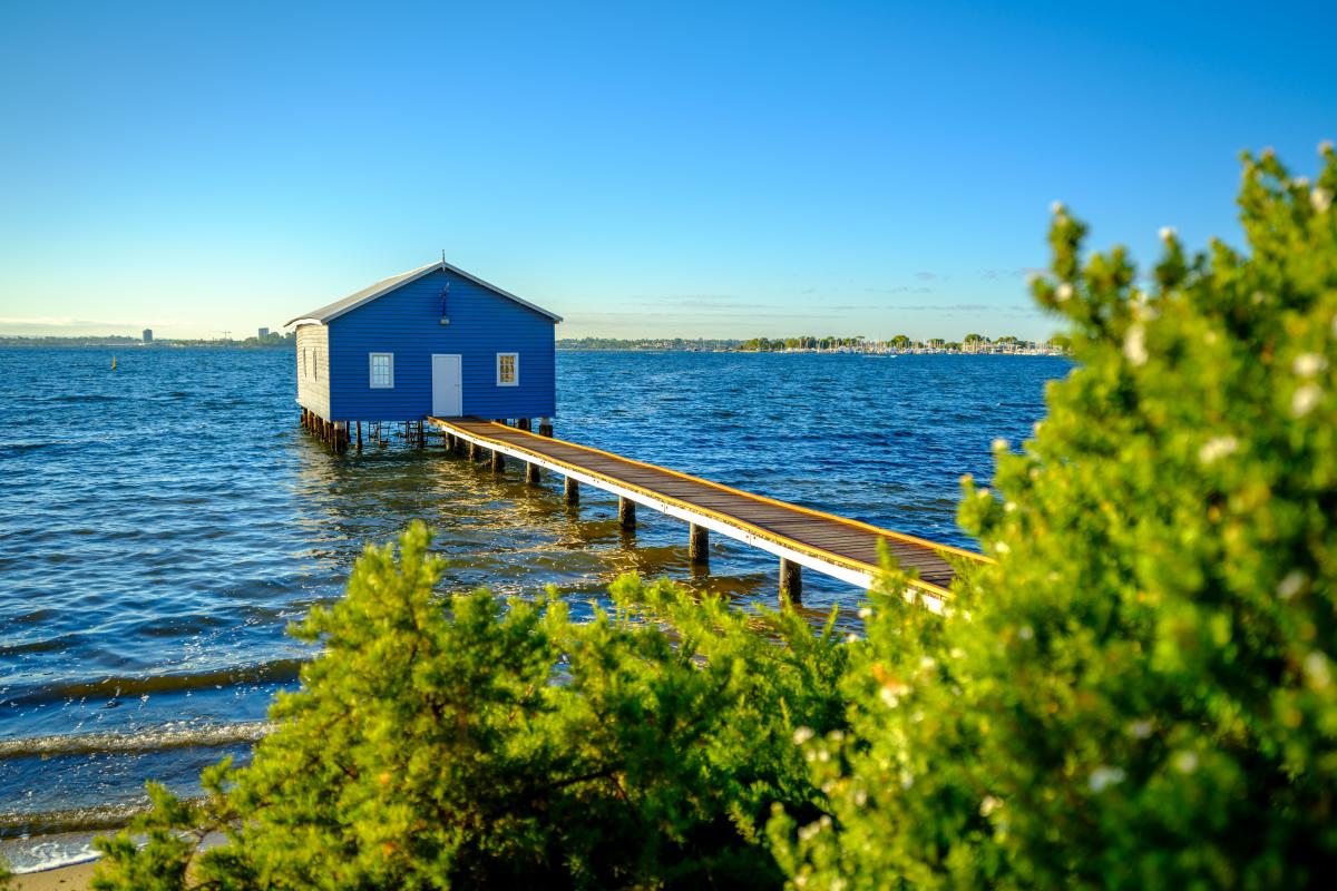 blue boat house with small jetty over water