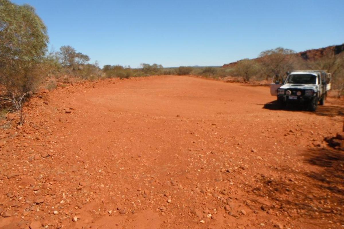 A natural basin of red dirt with work vehicle in the foreground.