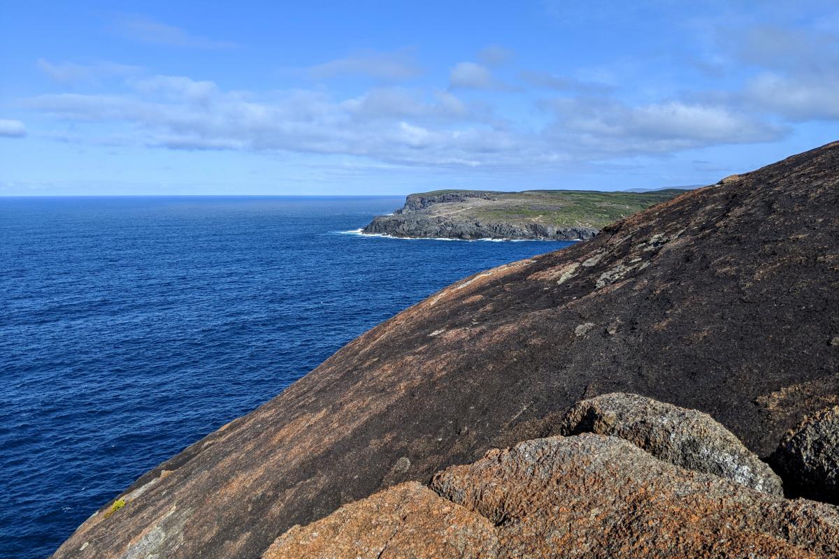 Round granite headland of Torbay Head with blue ocean and the cliffs of West Cape Howe in the distance