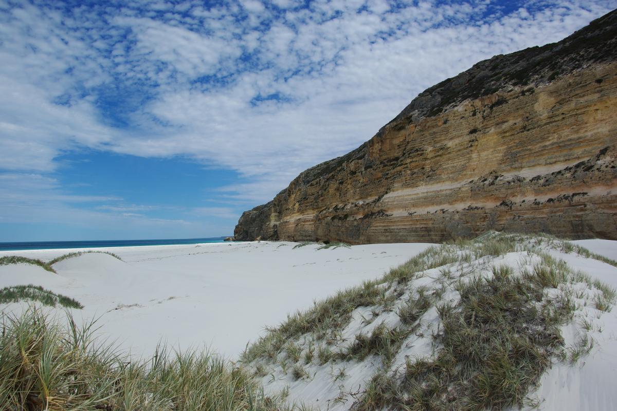 High cliffs with white sand dunes and blue water make a stunning contrast.