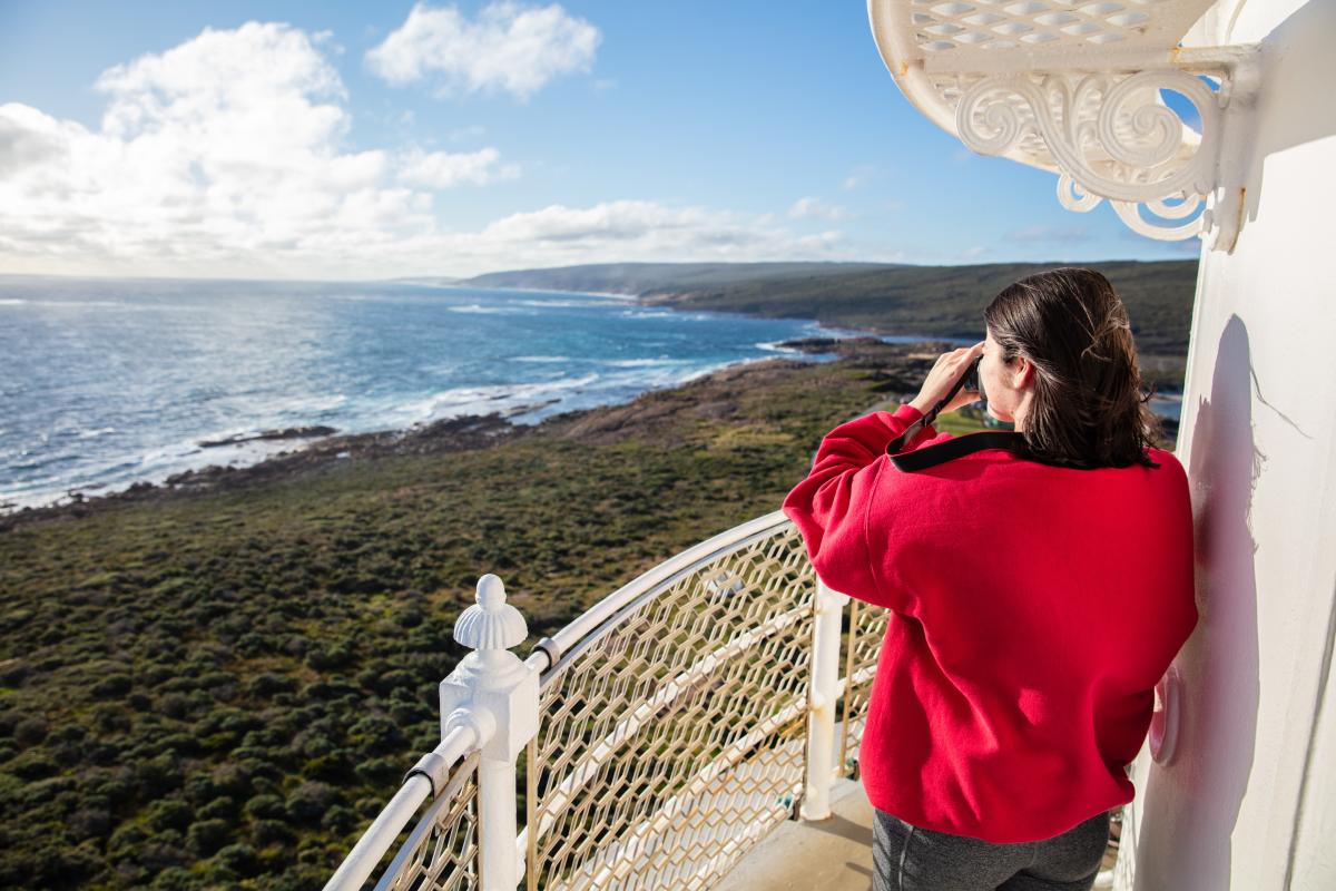 Person standing on lighthouse looking at the view over the ocean