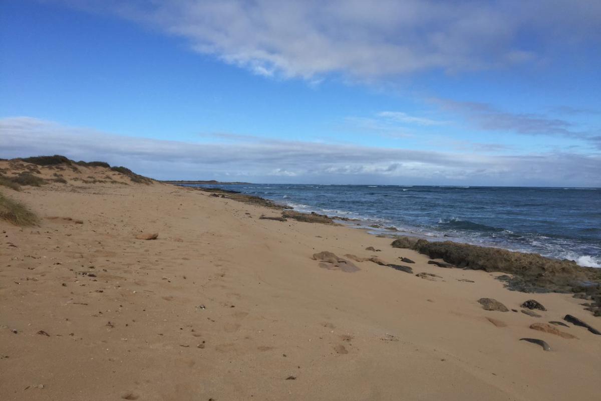 wide sandy beach beside a deep blue sea with building clouds at Five Mile