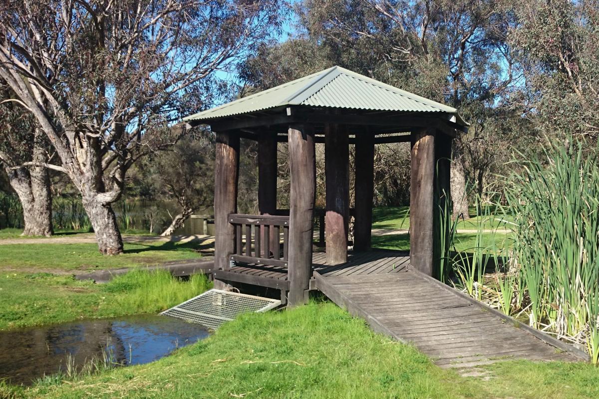 An interesting timber shade shelter spans a waterway between lakes.