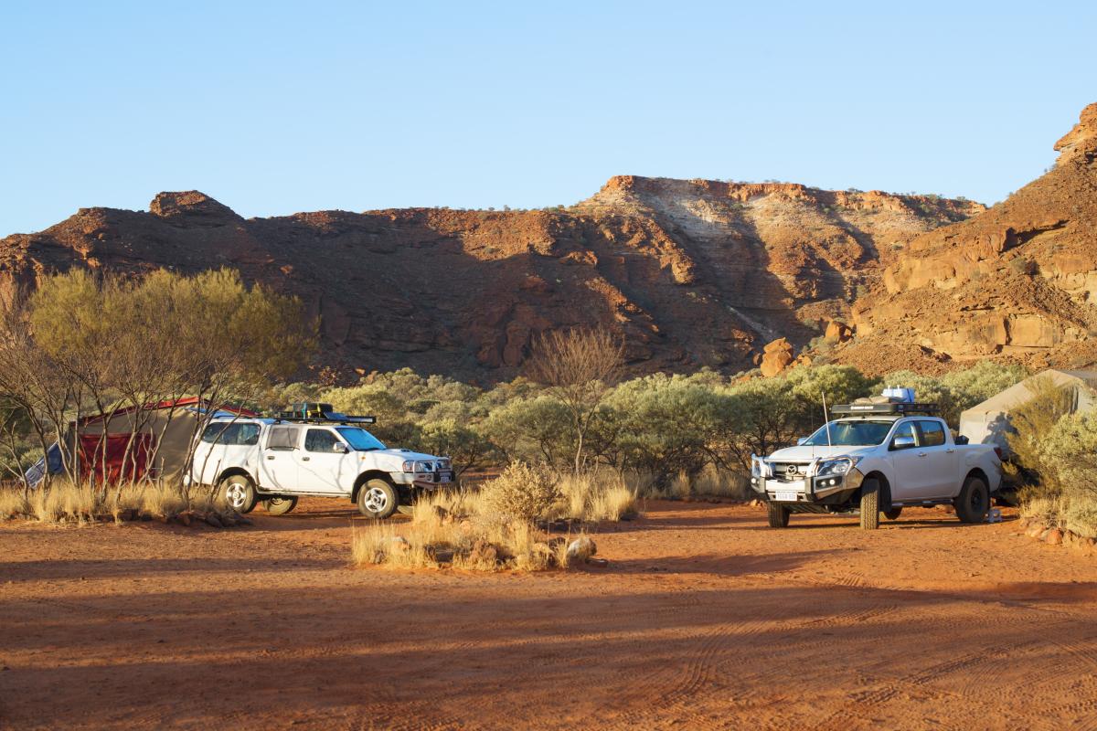 Two four-wheel drive vehicles parked on red dirt