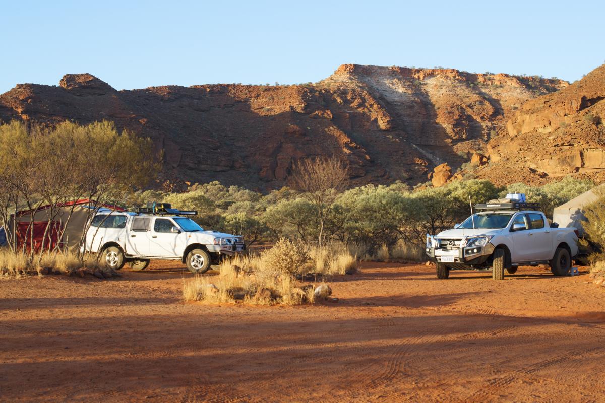 Two four-wheel drive vehicles parked on red dirt