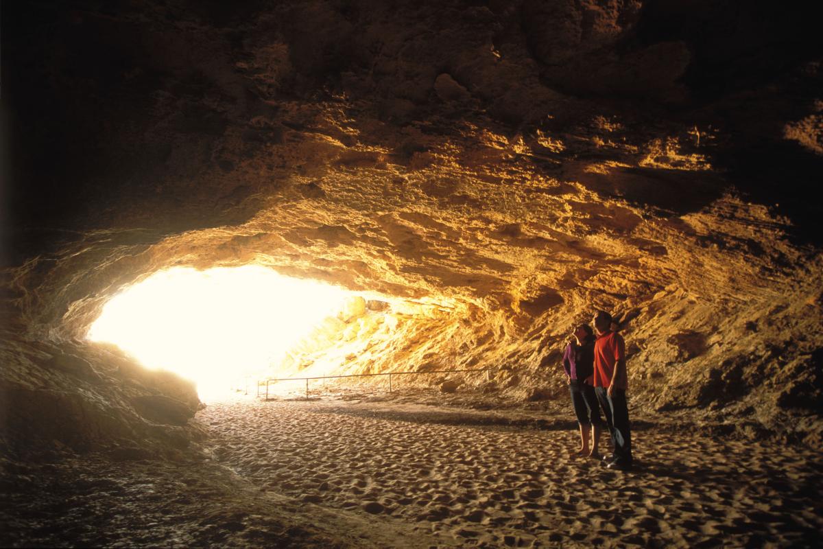 Two people standing in a cave looking at the ceiling. 