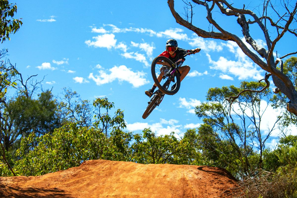 a mountain bike rider in the air over the gravel track