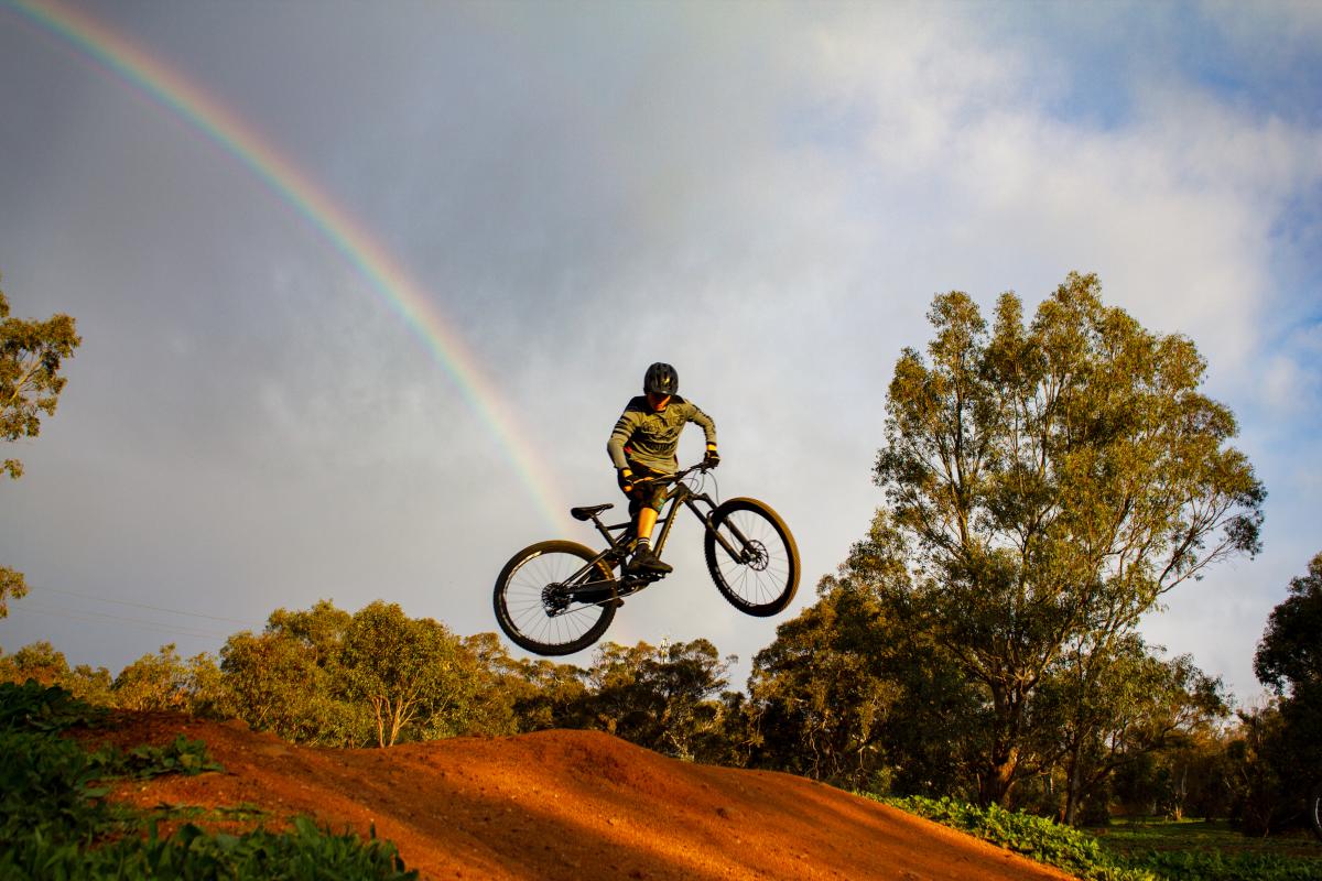 a rainbow behind a mountain biker
