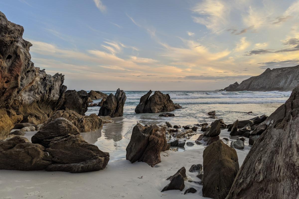 jagged rocks on the white sands of Whalebone Cove with waves in the background