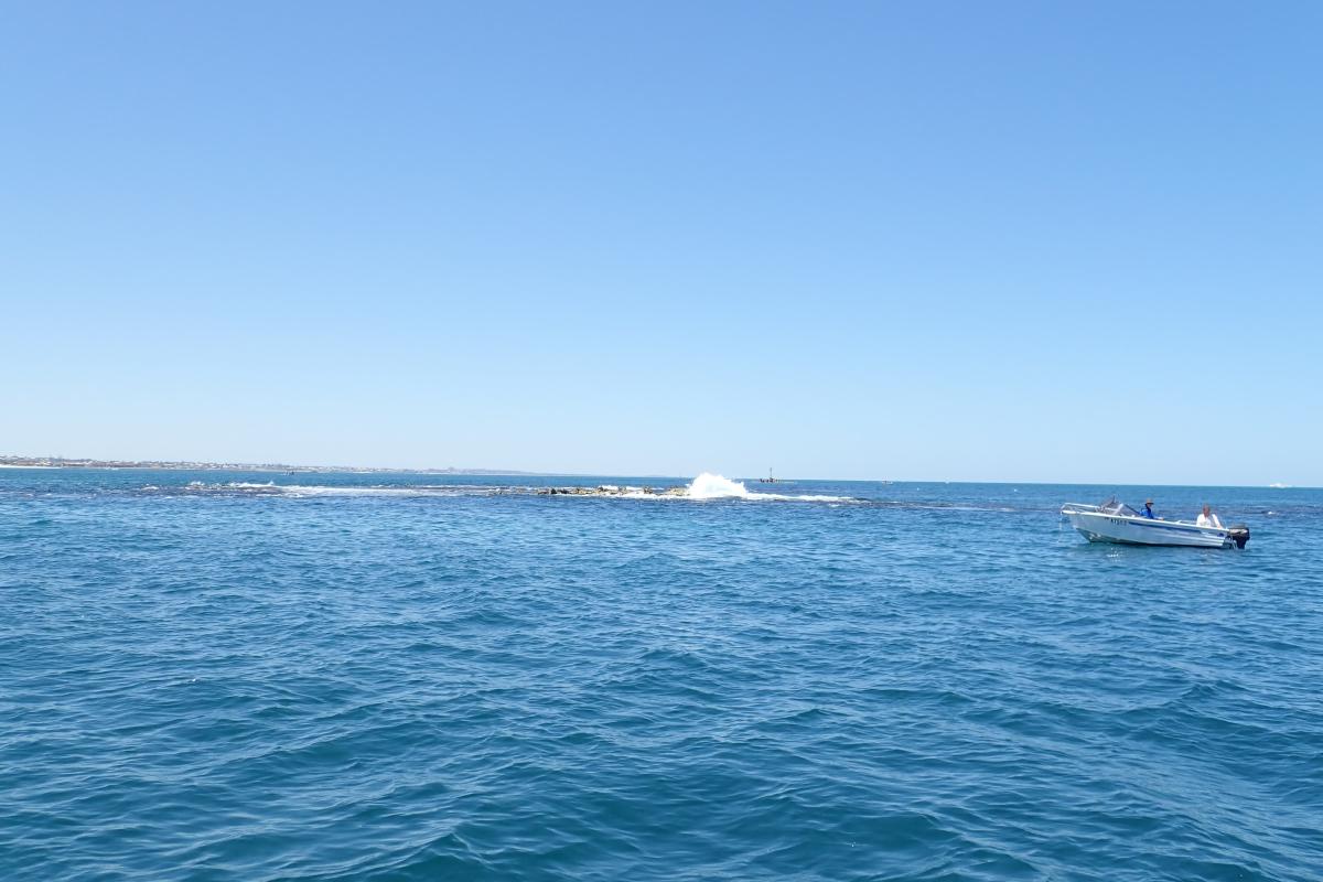 Small boat around the blue waters of Whitfords Rock