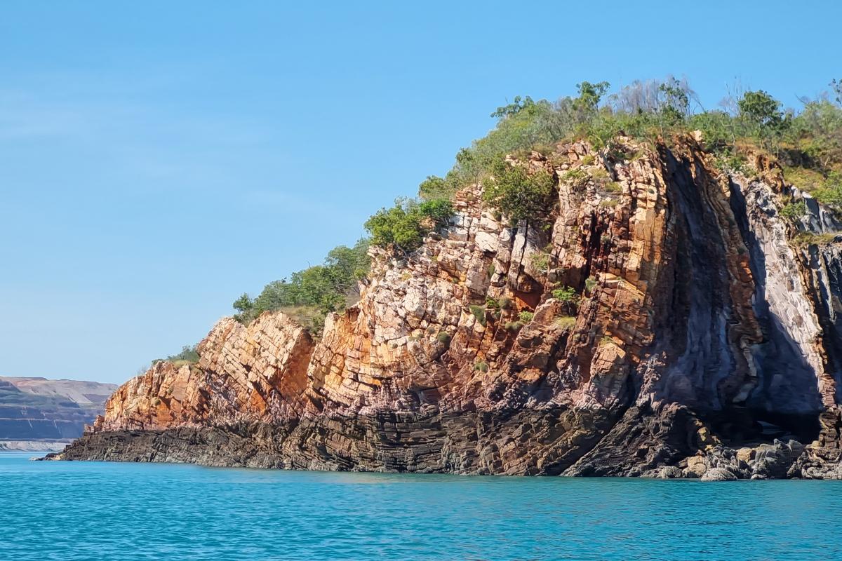 Rock formations covered in shrubs leading to the ocean