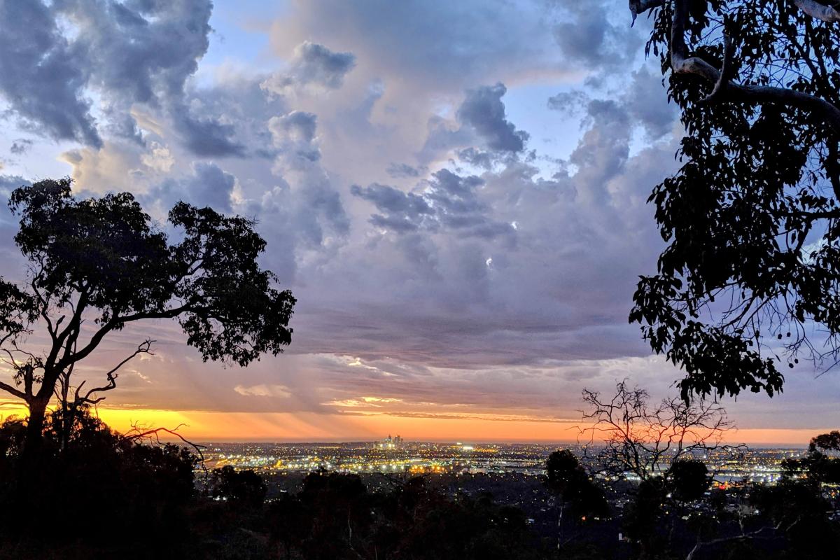 Lights of Perth City and storm clouds at sunset viewed from Lewis Road Walk Trail in Mundy Regional Park
