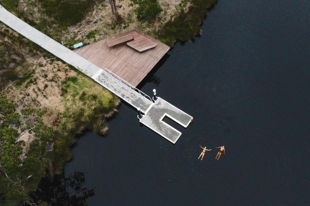 Floating around at the Nornalup Jetty Aerial view of a jetty and two people floating in water.