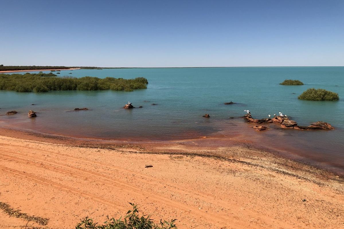 Red sand beach with blue waters.