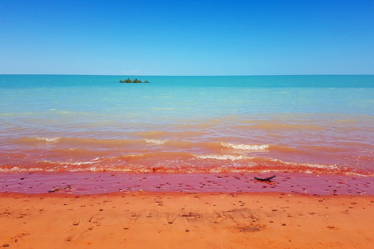 Man galagun (Crab Creek) Bright blue waters with pindan red sandy beach.