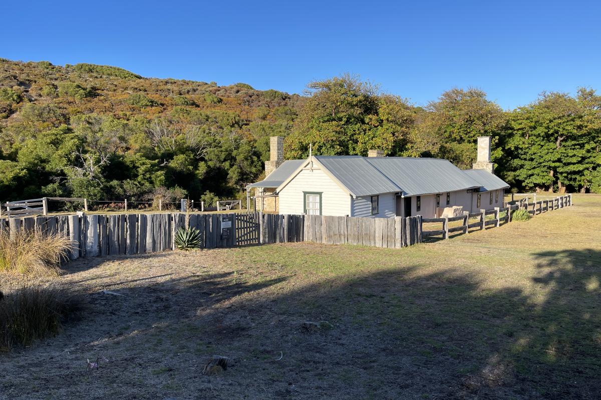 Historic house surrounded by wooden fence.