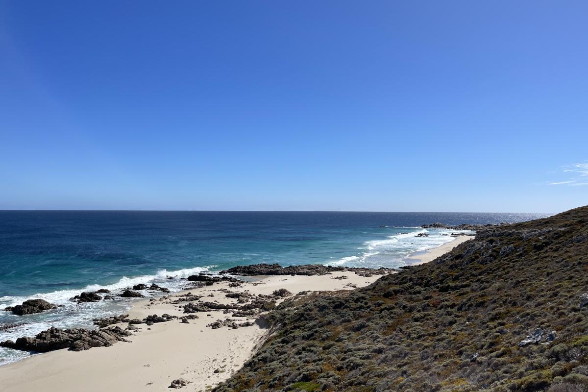 Landscape of rocks leading to sandy beach. 