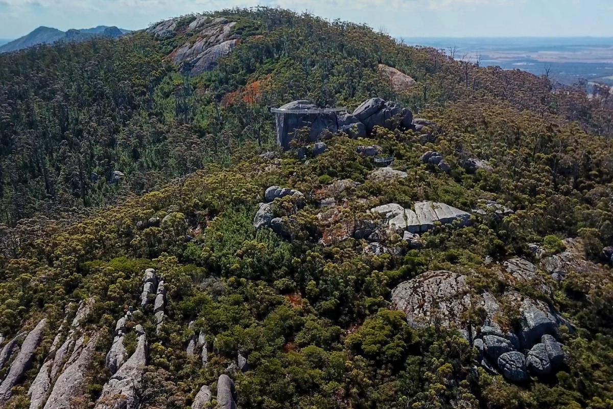 Large granite rocks amongst green trees and shrubs in a mountainous area.