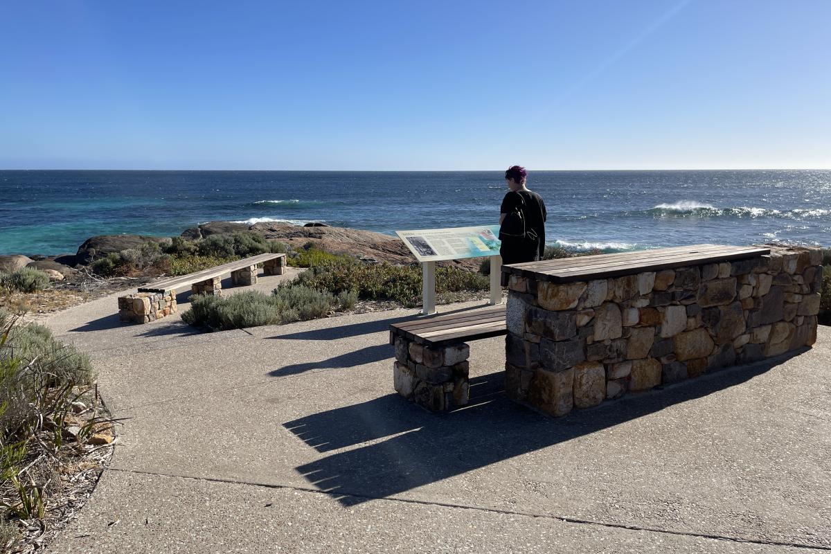 Concrete paths and interpretive signage overlooking beach.