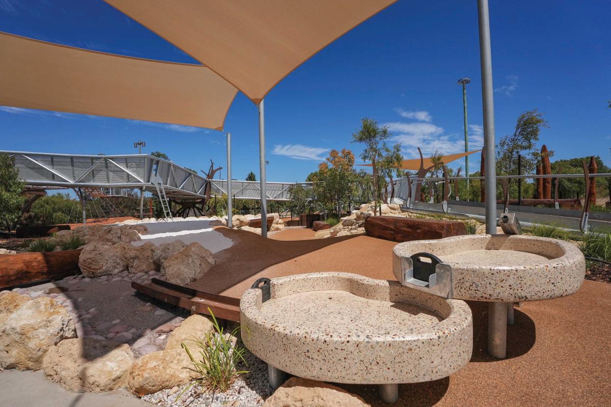 Close up of concrete accessible facilities in a playground under a shelter.