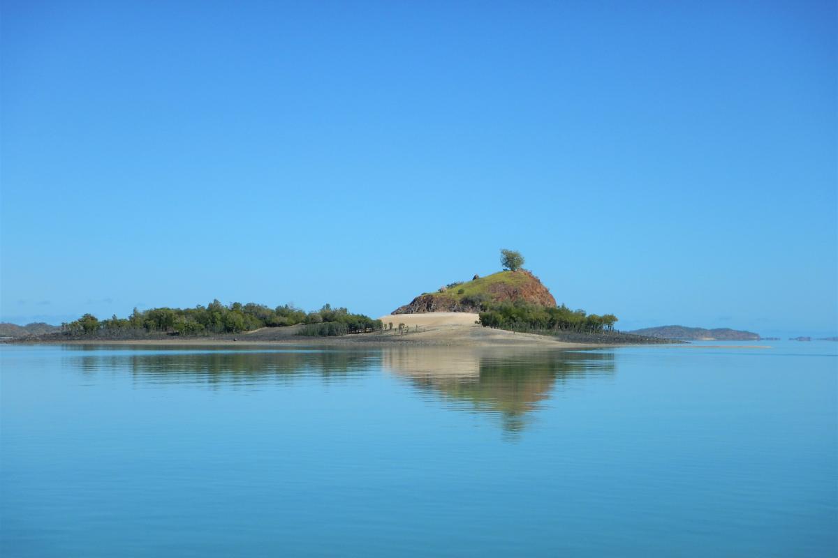 Barrali (Strickland Bay) Island surrounded by clear ocean, clam and reflecting the island.
