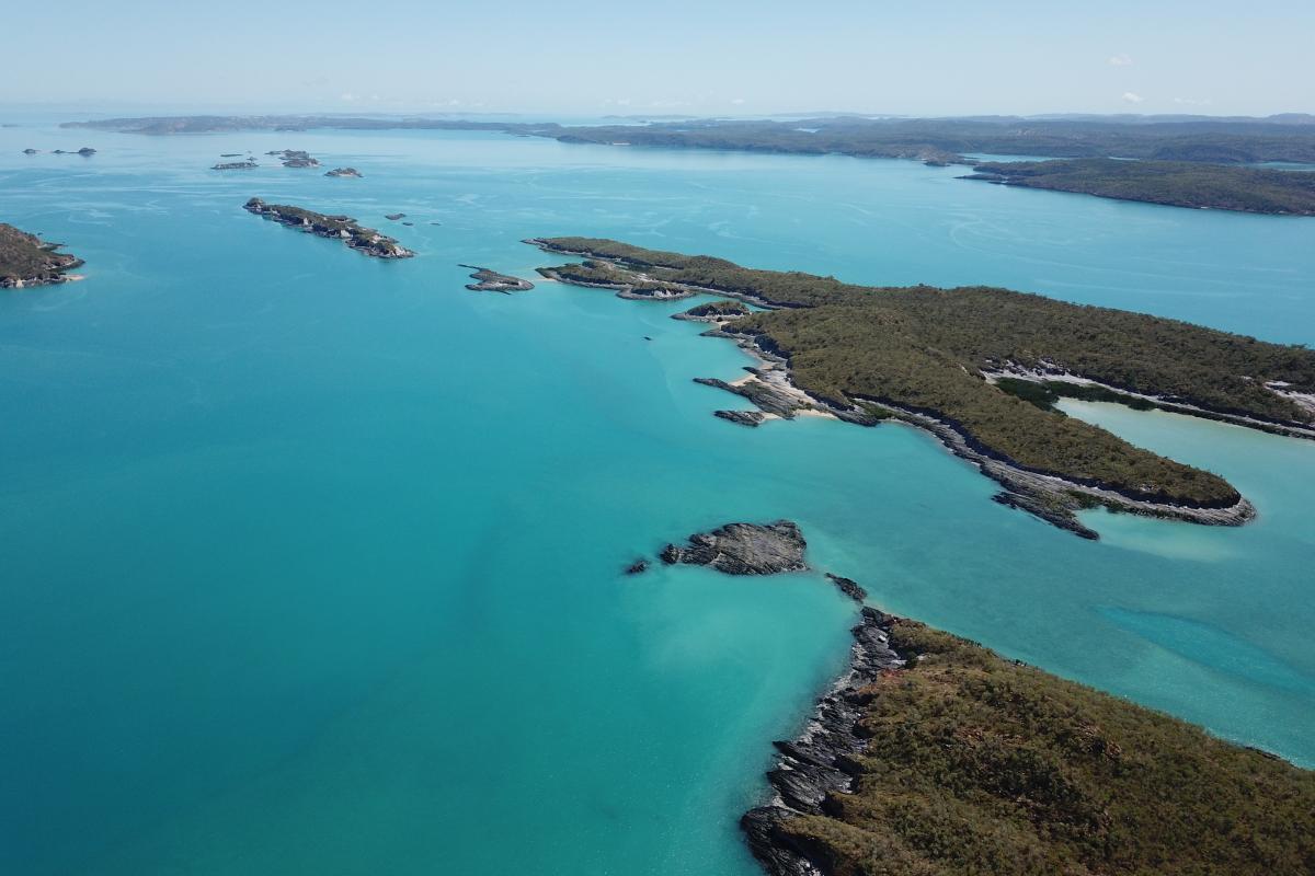 Aerial view of islands surrounded by green ocean. 