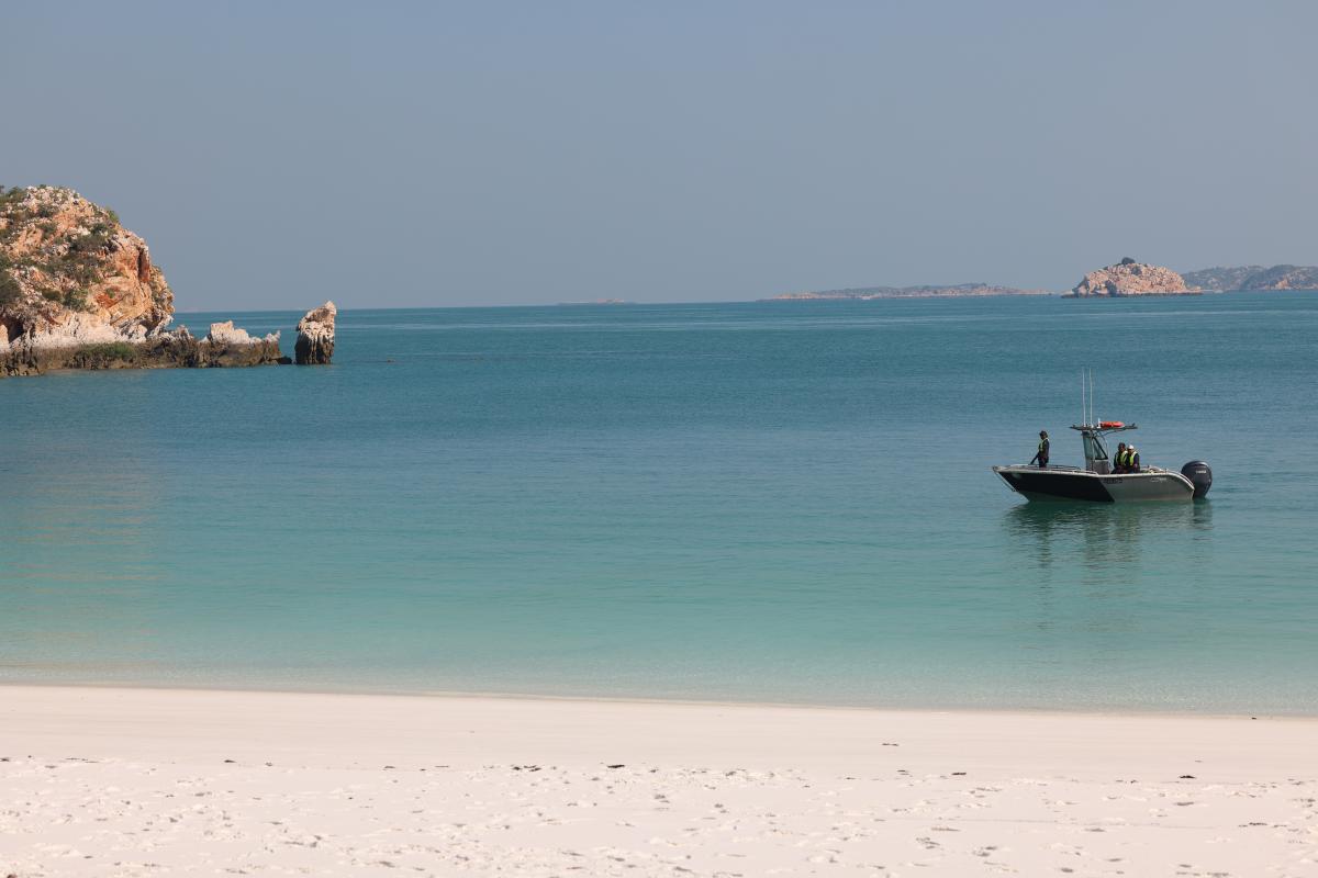 Person in small dinghy near beach.