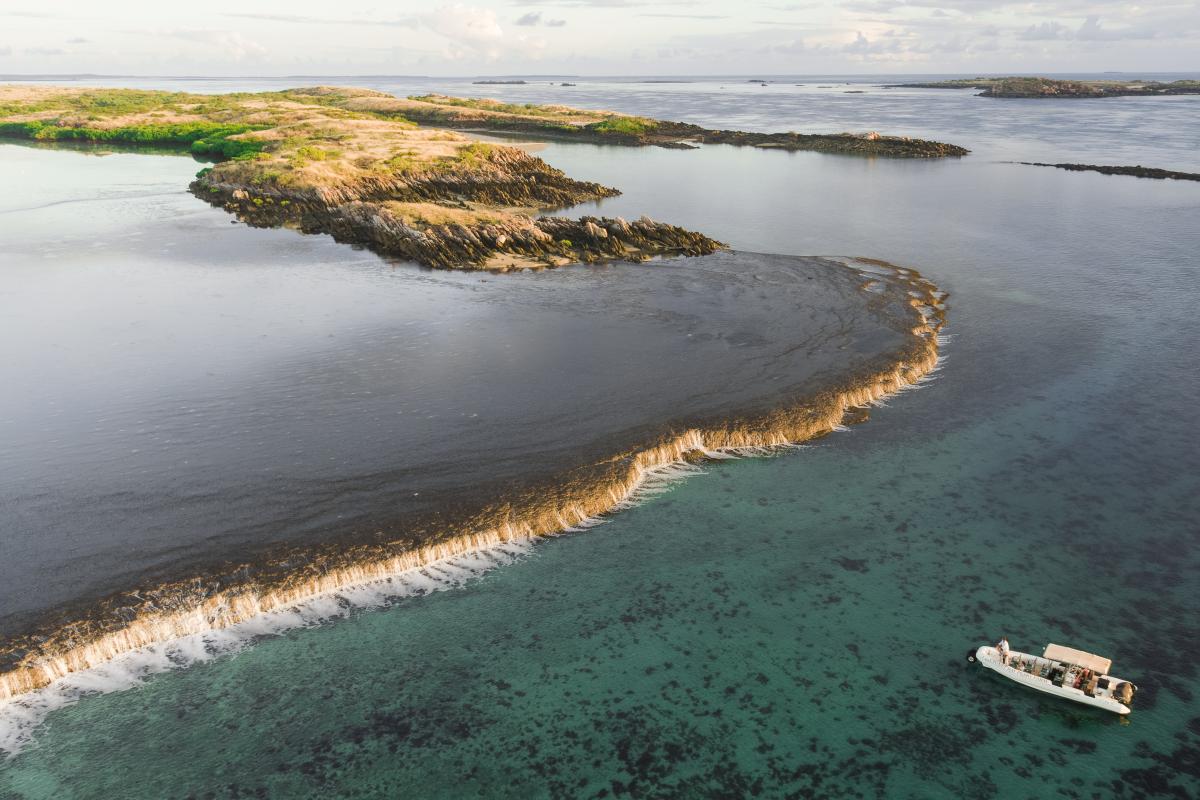 Aerial view of boat near exposed reef. 