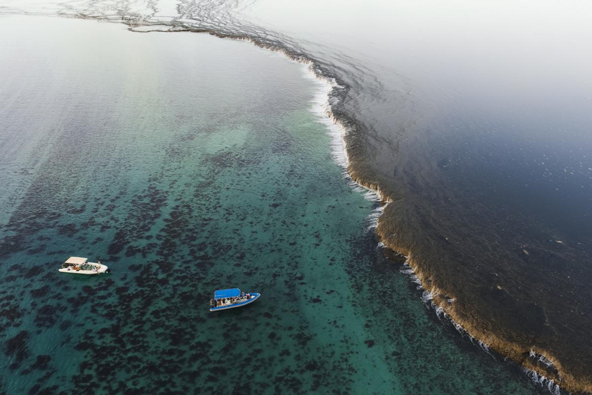 Aerial view of boat near exposed reef.