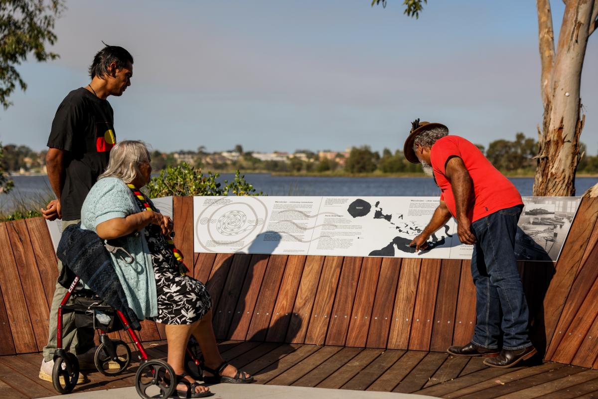 People reading signage near the river. 