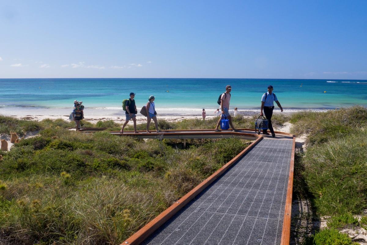 Houtman Abrolhos Islands National Park People walking on a boardwalk away from a beach.