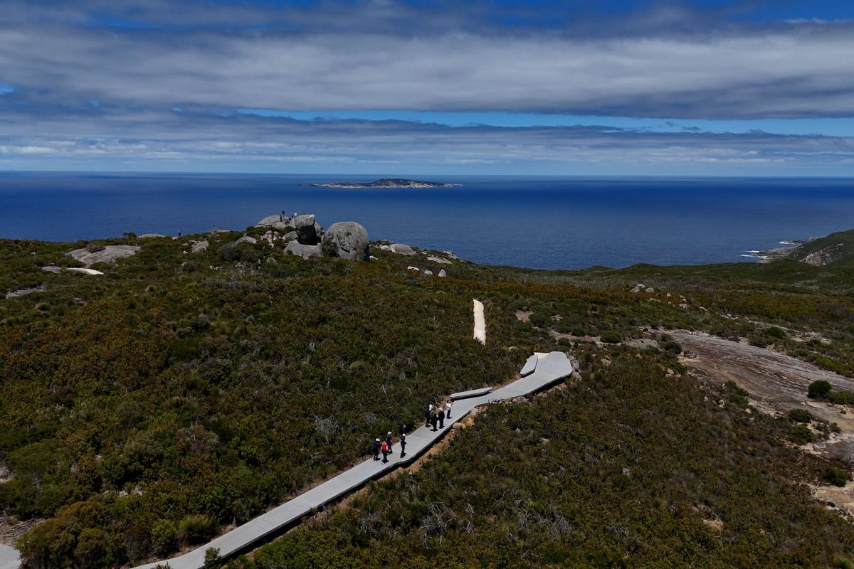 Aerial view of people walking up a path to the top of a hill. 
