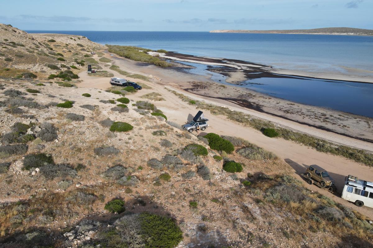 Aerial view of sandy campsites by the beach. 