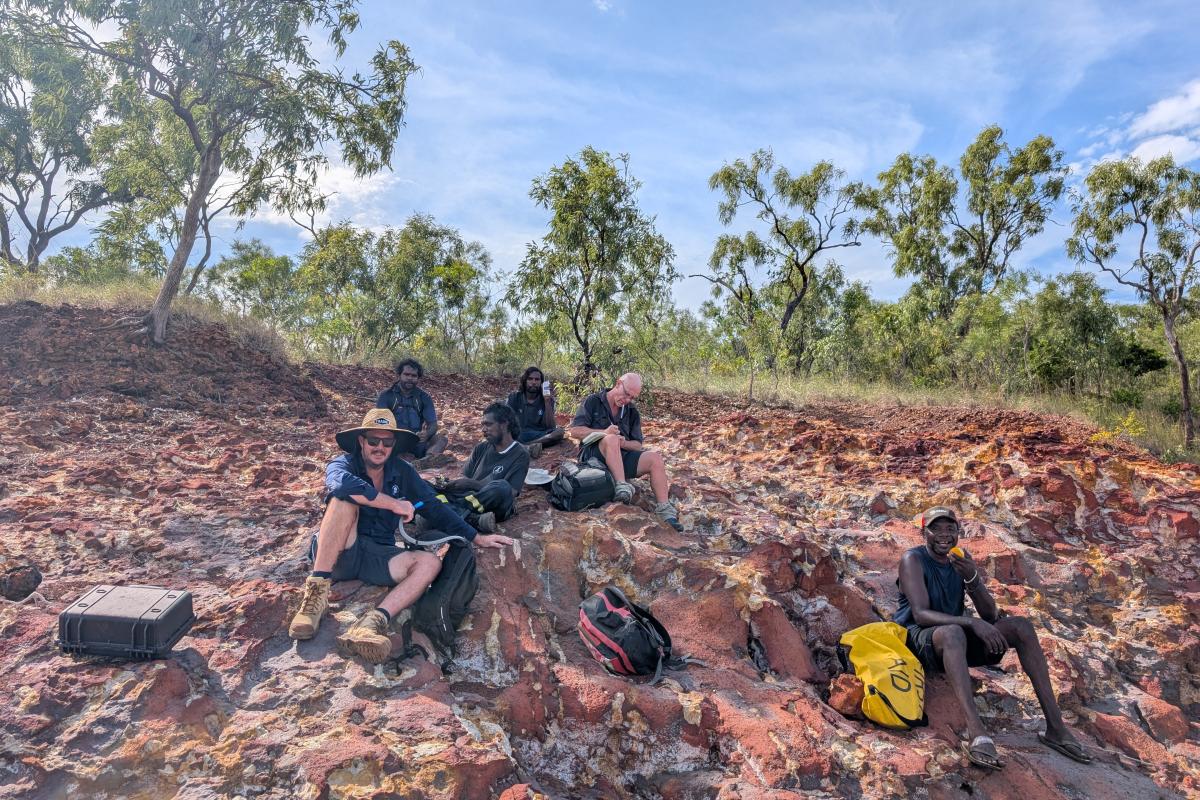 Group of people sitting on red rocks.