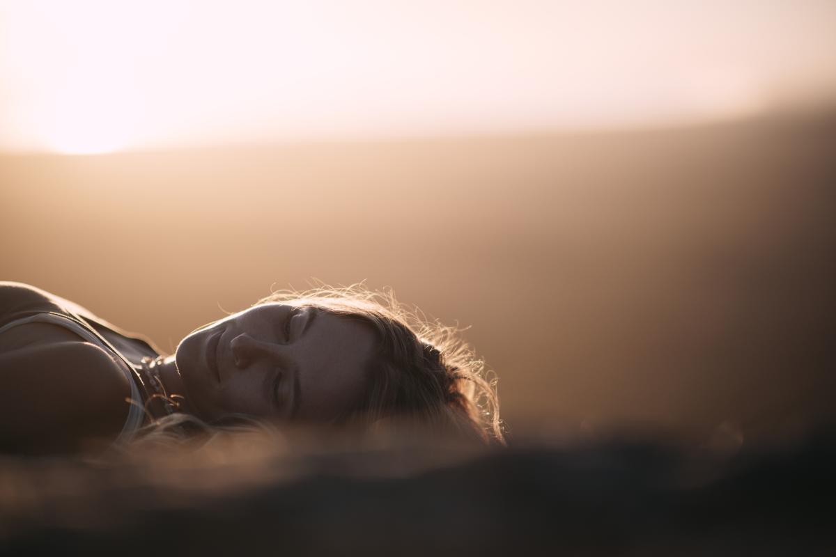 Close up of person's face lying on the ground smiling with sunset colours. 